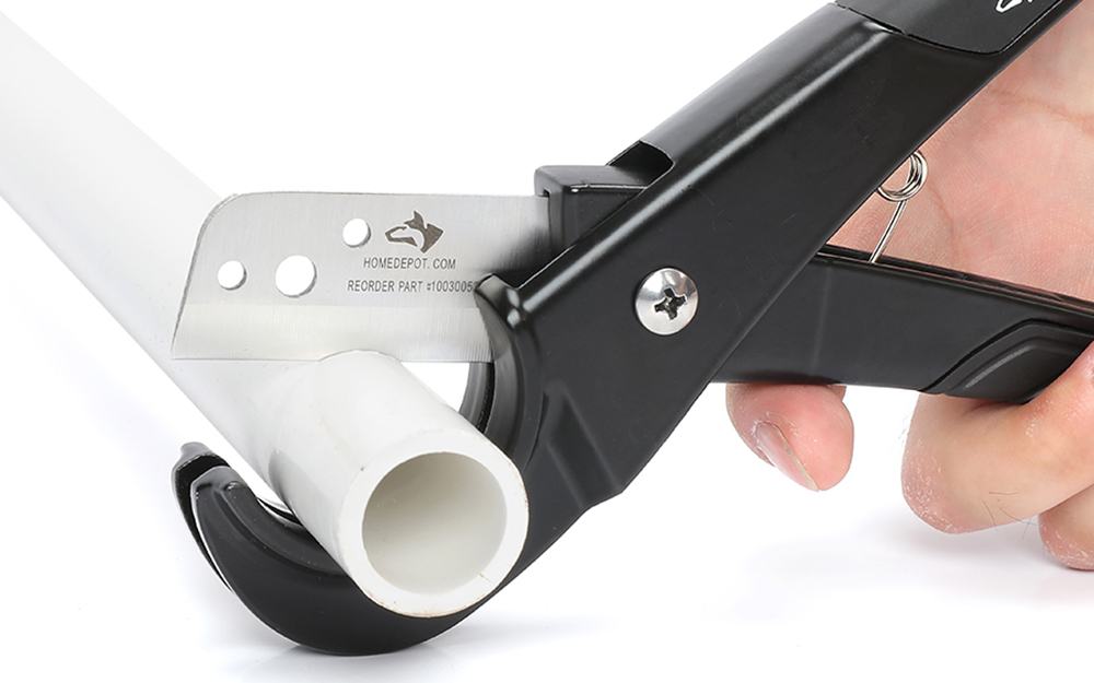 บุคคลใช้เครื่องตัดท่อ PEX บนชิ้นส่วนของท่อ PEX A person uses a PEX tubing cutter on a piece of PEX tubing.